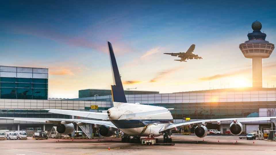 Großes Passagierflugzeug am Gate, während im Hintergrund ein weiteres Flugzeug landet.
