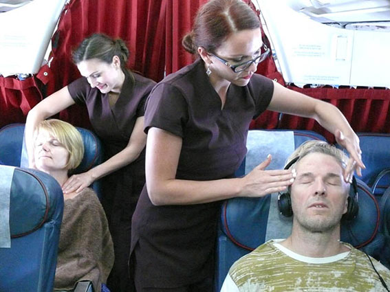 Stewardessen masseren het hoofd en de schouders van passagiers aan boord van een vliegtuig.