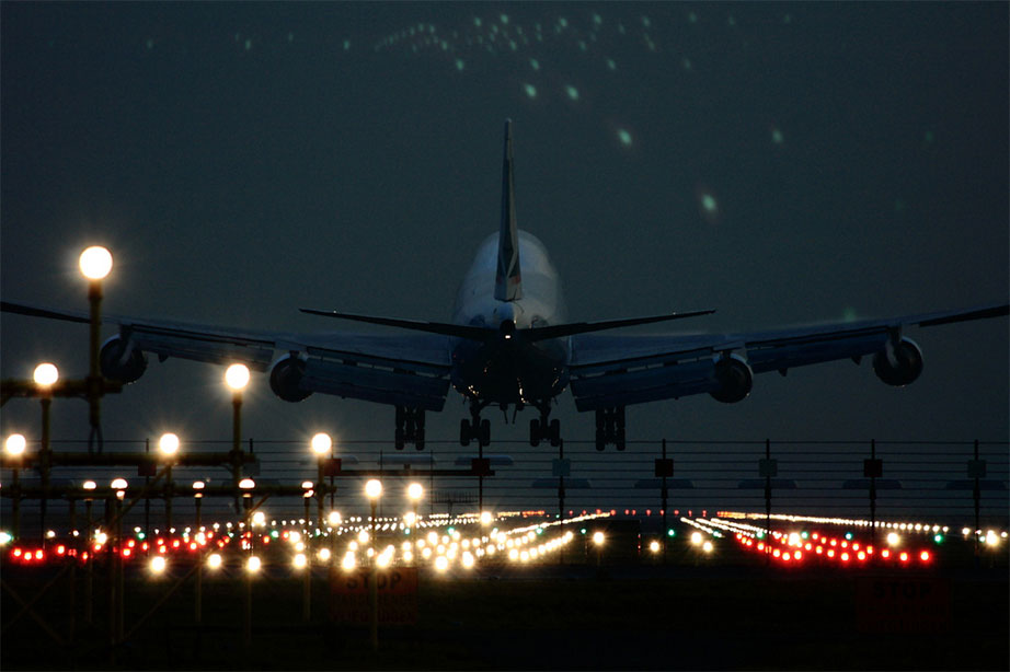 vliegtuig aan het landen op verlichte landingsbaan in de avond