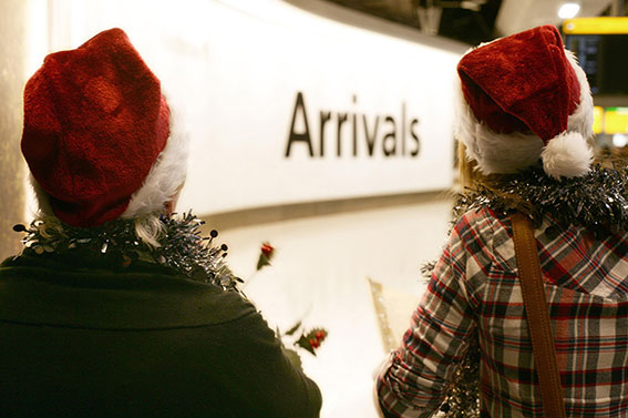 passagiers met kerstmutsen op bij arrivals bord