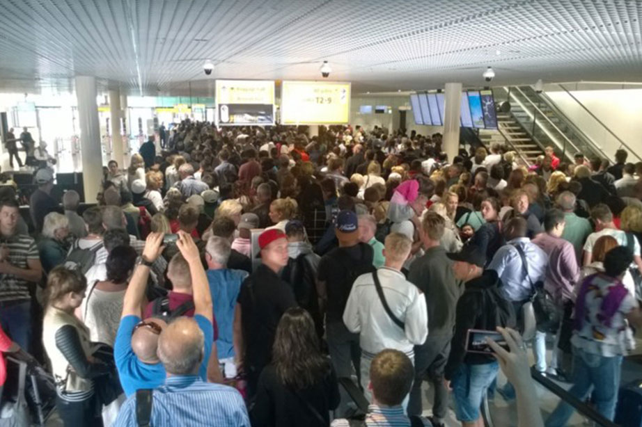 wachtende passagiers in drukke vertrekhal Schiphol