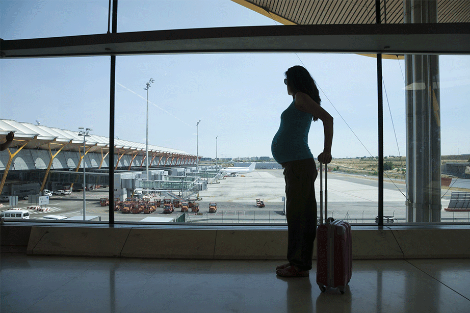 zwangere vrouw voor het raam op vliegveld