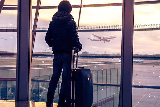 passagier voor raam op vliegveld met koffer