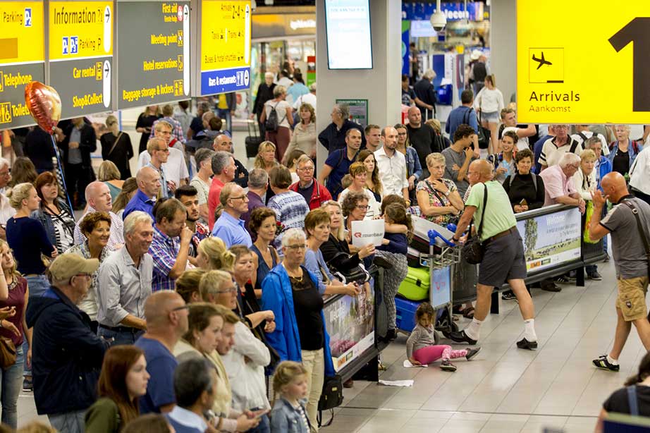 drukte wachtende passagiers bij aankomsthal Schiphol