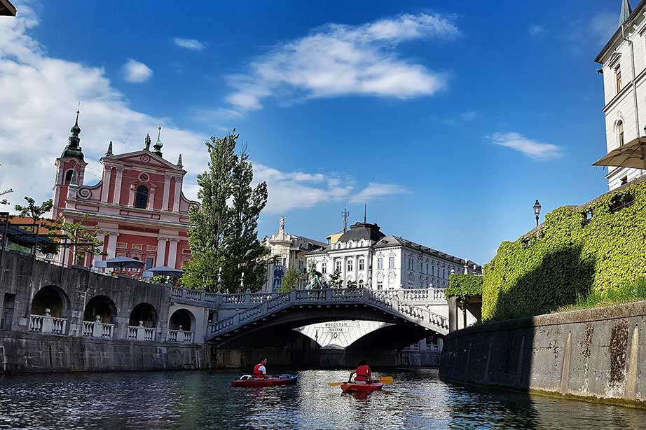 ljubljana stad vanaf het water met een brug en kanoërs