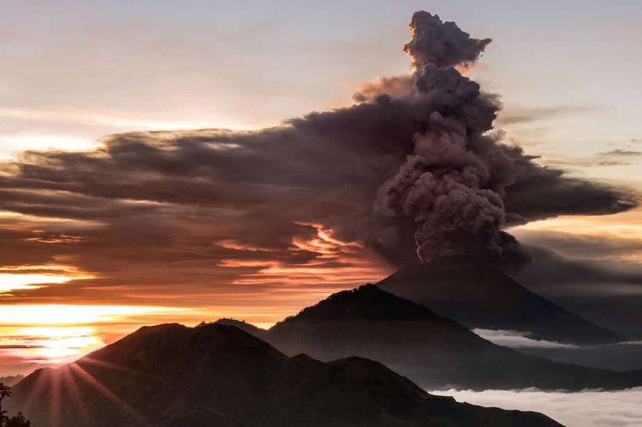 vulkaan met grote aswolk bij zonsondergang