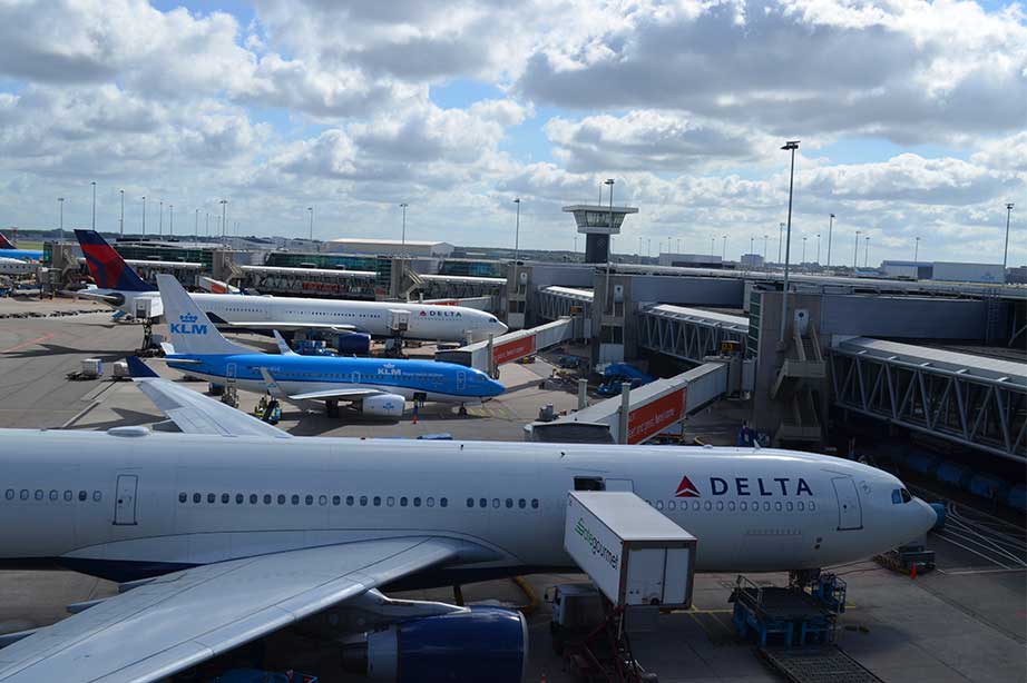 vliegtuigen delta en klm geparkeerd op schiphol met bewolkte lucht