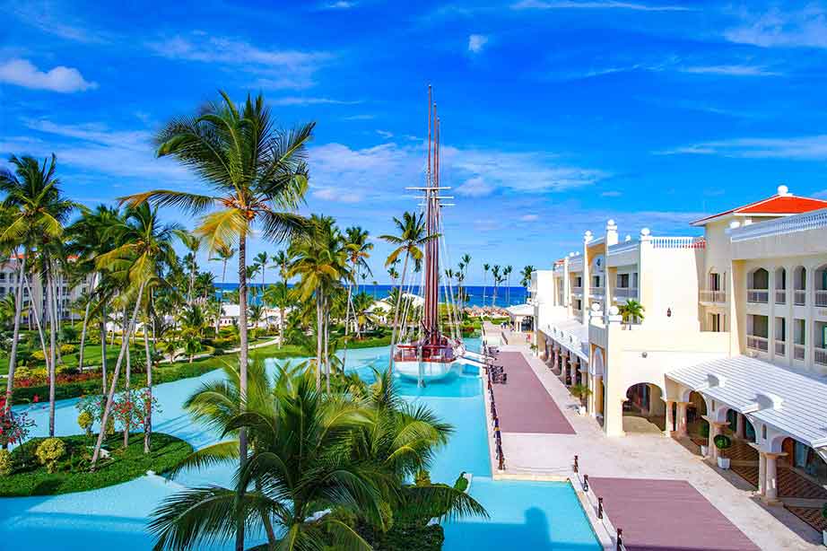hotel met zwembad en palmbomen met uitzicht over de zee en een blauwe lucht