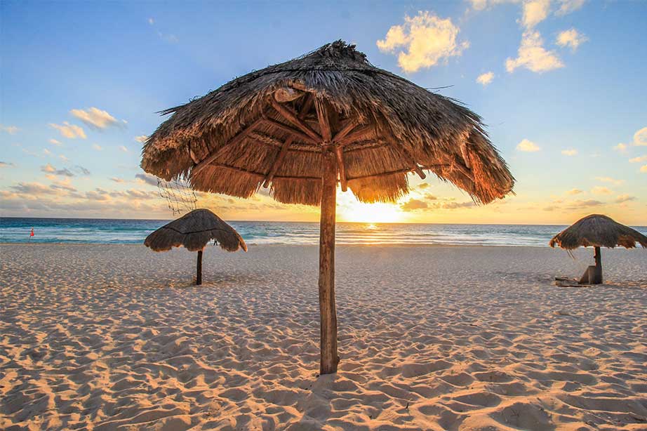 strand met rieten parasol, zee en zonsondergang