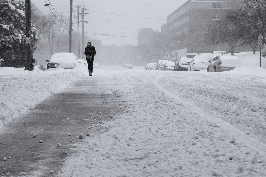 man loopt door sneeuw op straat