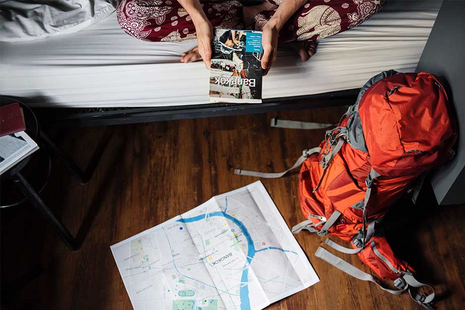 meisje op bed in hostel met backpack en kaart bangkok