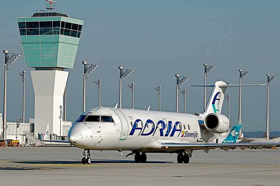 adria airways vliegtuig op de landingsbaan bij verkeerstoren