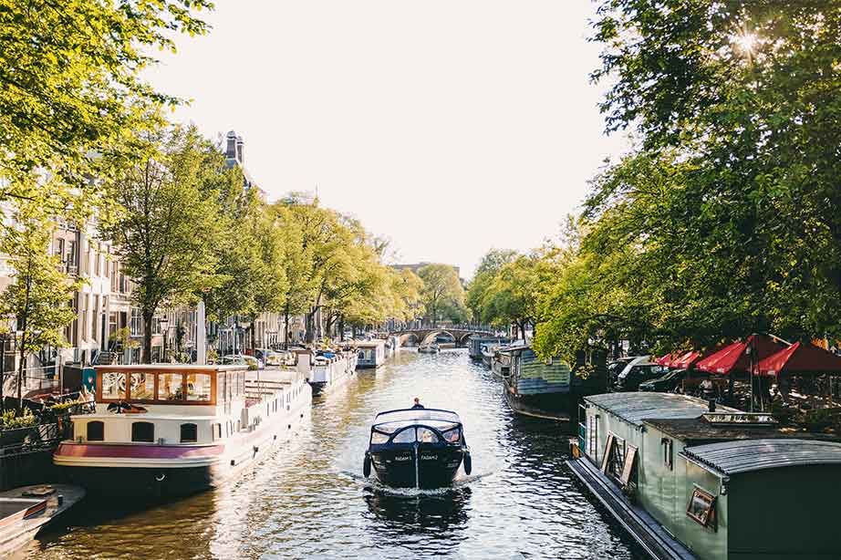 boot op nederlandse grachten amsterdam met bomen eromheen