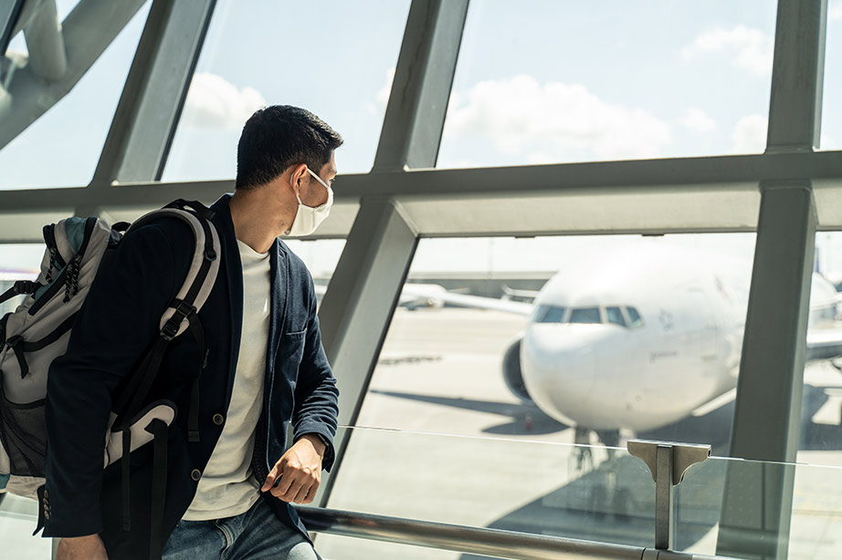 passagier met mondkopje kijkt naar vliegtuig