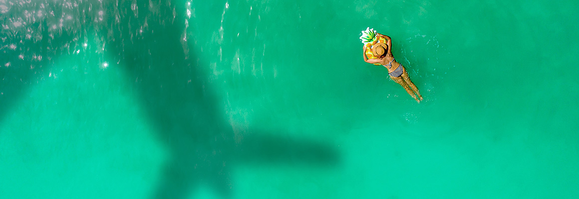 meisje dobbert in het water met schaduw van een vliegtuig boven haar