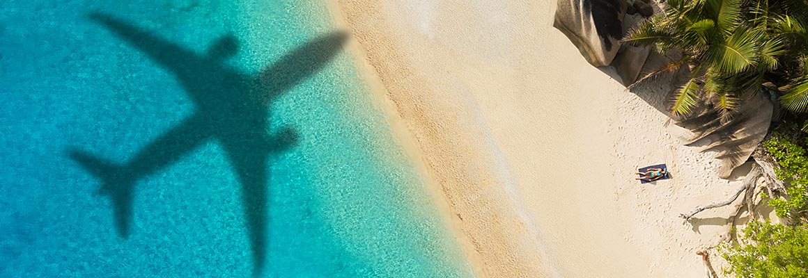 Schaduw van een vliegtuig over een wit strand