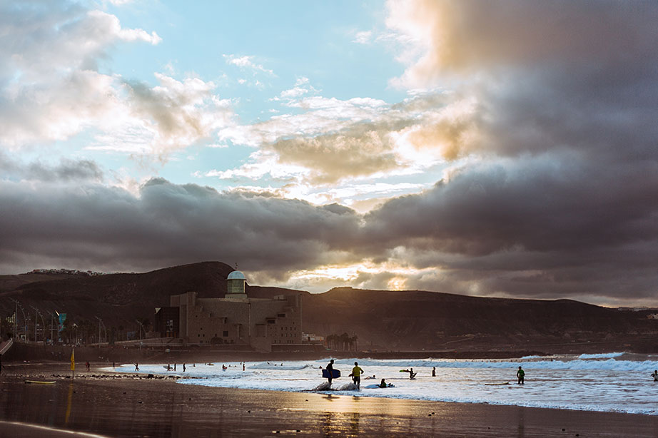 Surfers staan op het strand in Gran Canaria terwijl het donker begint te worden