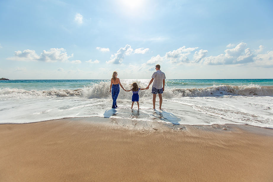 Familie loopt op het strand met een zonnetje