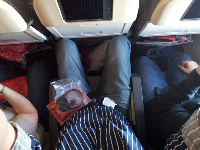 Afbeelding van een passagier met beperkte beenruimte tijdens een vlucht.