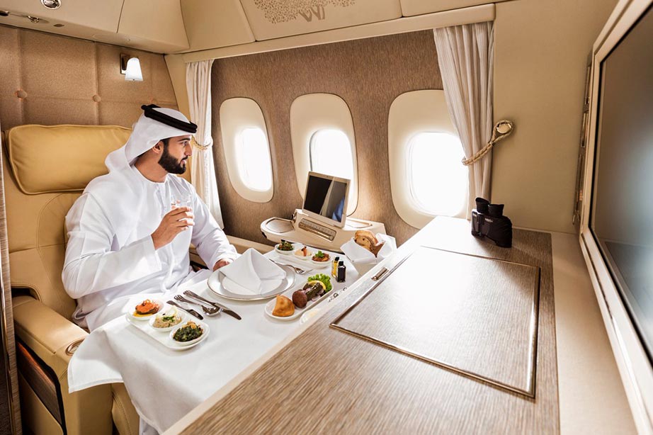 Een man zit te genieten van zijn eten in het first class gedeelte van Emirates