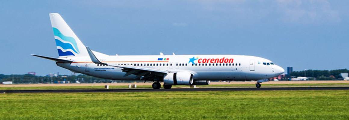 corendon vliegtuig landt op vliegveld bij blauwe lucht en groen grasveld