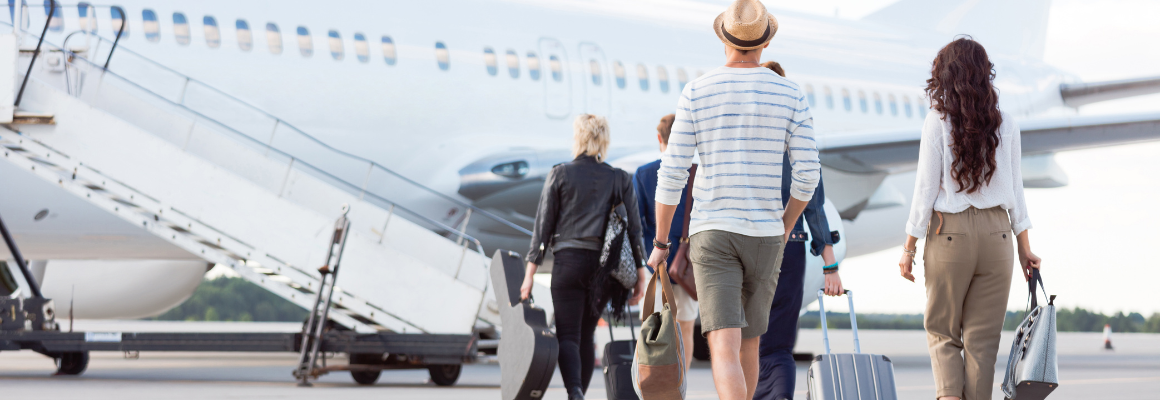 Passagiers lopen over het vliegveld richting een vliegtuigtrap om aan boord te gaan van een vliegtuig, met bagage in de hand