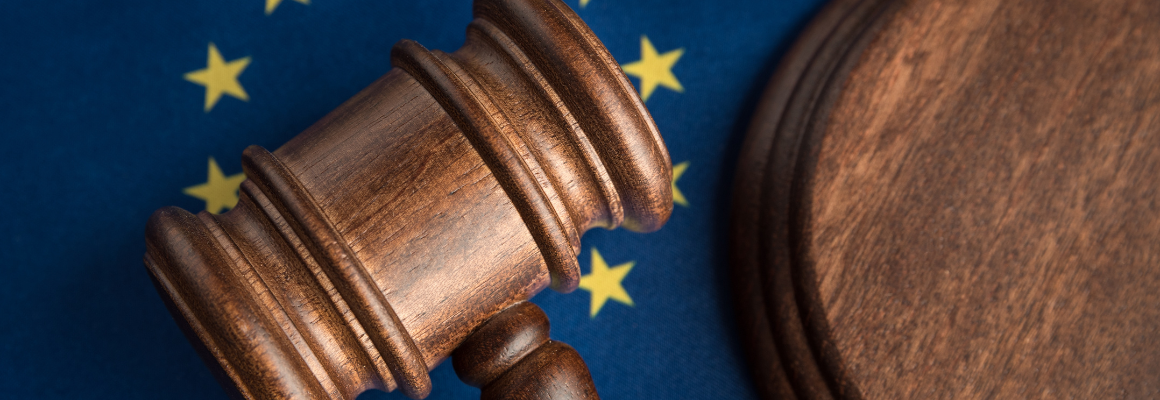 Houten rechtershamer op een ondergrond met de vlag van de Europese Unie, herkenbaar aan de blauwe achtergrond met gele sterren.