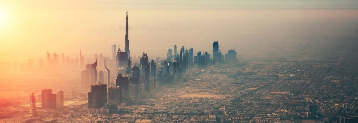 Moderne skyline met hoge wolkenkrabbers en palmbomen onder een heldere blauwe lucht, waarschijnlijk in een warme stad als Dubai