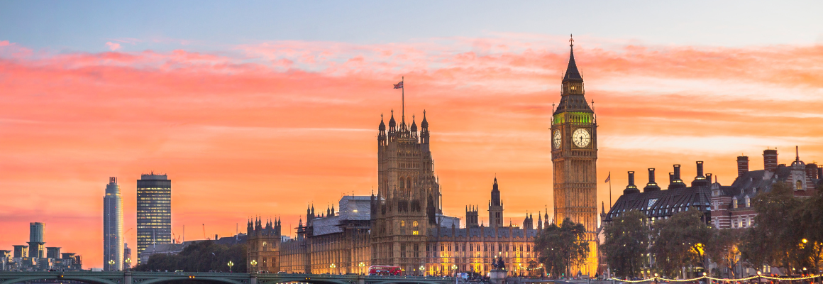 Zonsondergang over Londen met de Thames, de Houses of Parliament en Big Ben op de voorgrond, met een vliegtuig dat over de stad vliegt